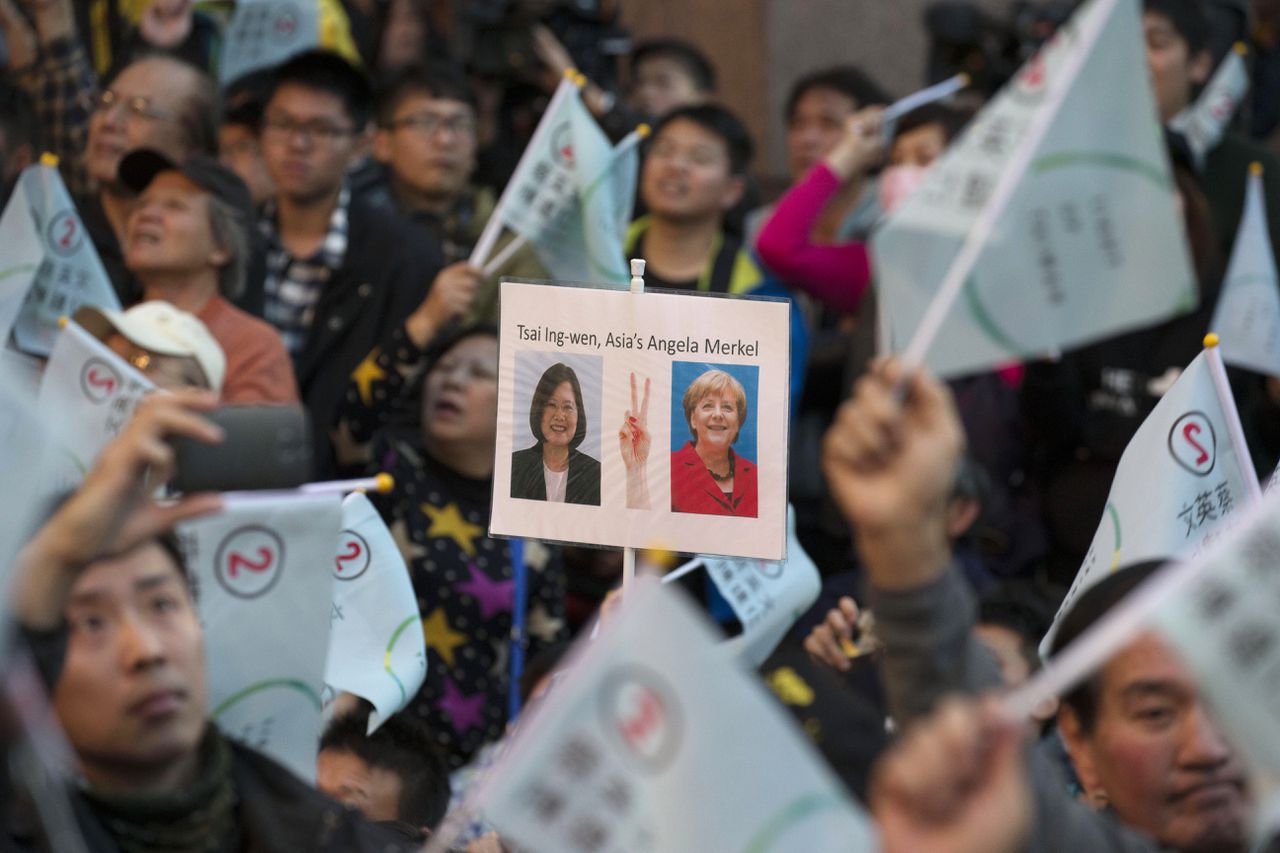 Een aanhanger van Tsai Ing-wen houdt een bord omhoog waarop de presidentskandidate wordt vergeleken met Merkel.