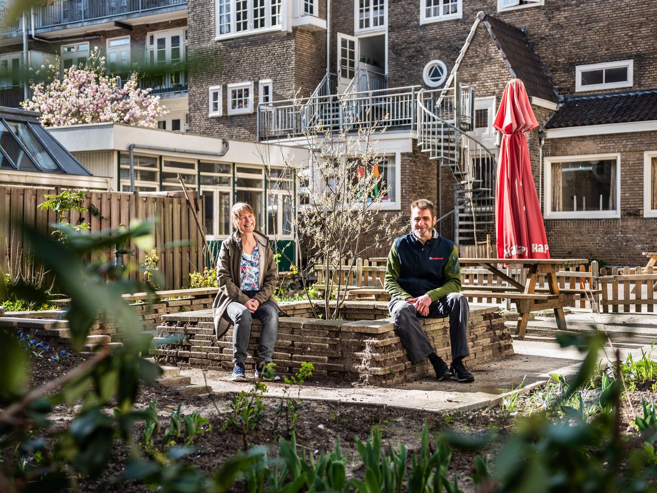 Luella van Turnhout van GroeneBuurten en Jowan Rijzinga, beheerder van Huis van de Wijk Lydia in Zuid, in de nieuwe binnentuin van het wijkcentrum: nu een regen- en hittebestendige voorbeeldtuin.