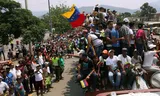 Venezolanen liften mee met de vrachtwagens met hulpgoederen onderweg naar de grens op zaterdag 23 februari.