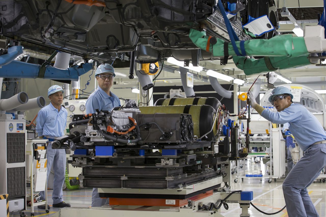 Een fabrieksarbeider installeert waterstoftanks in de Toyota Mirai. Aziatische fabrikanten investeren fors in de waterstofauto.