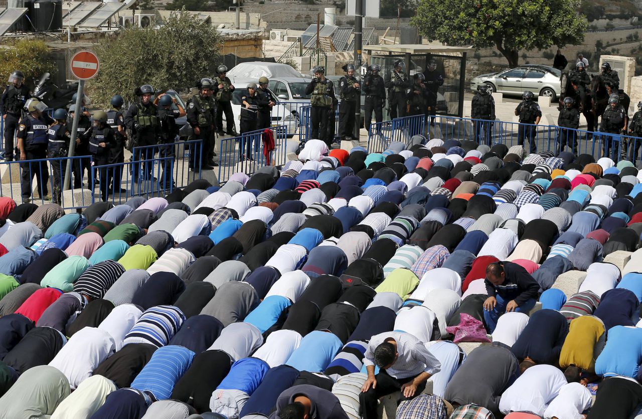 Palestijnen bidden in de Oude Stad. Israëlische agenten houden de wacht.