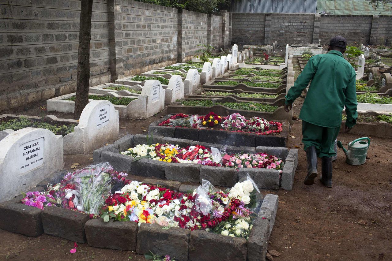 Een medewerker van een begraafplaats in Nairobi loopt langs de graven van bij de aanslag in het Westgate winkelcentrum gedode mensen.
