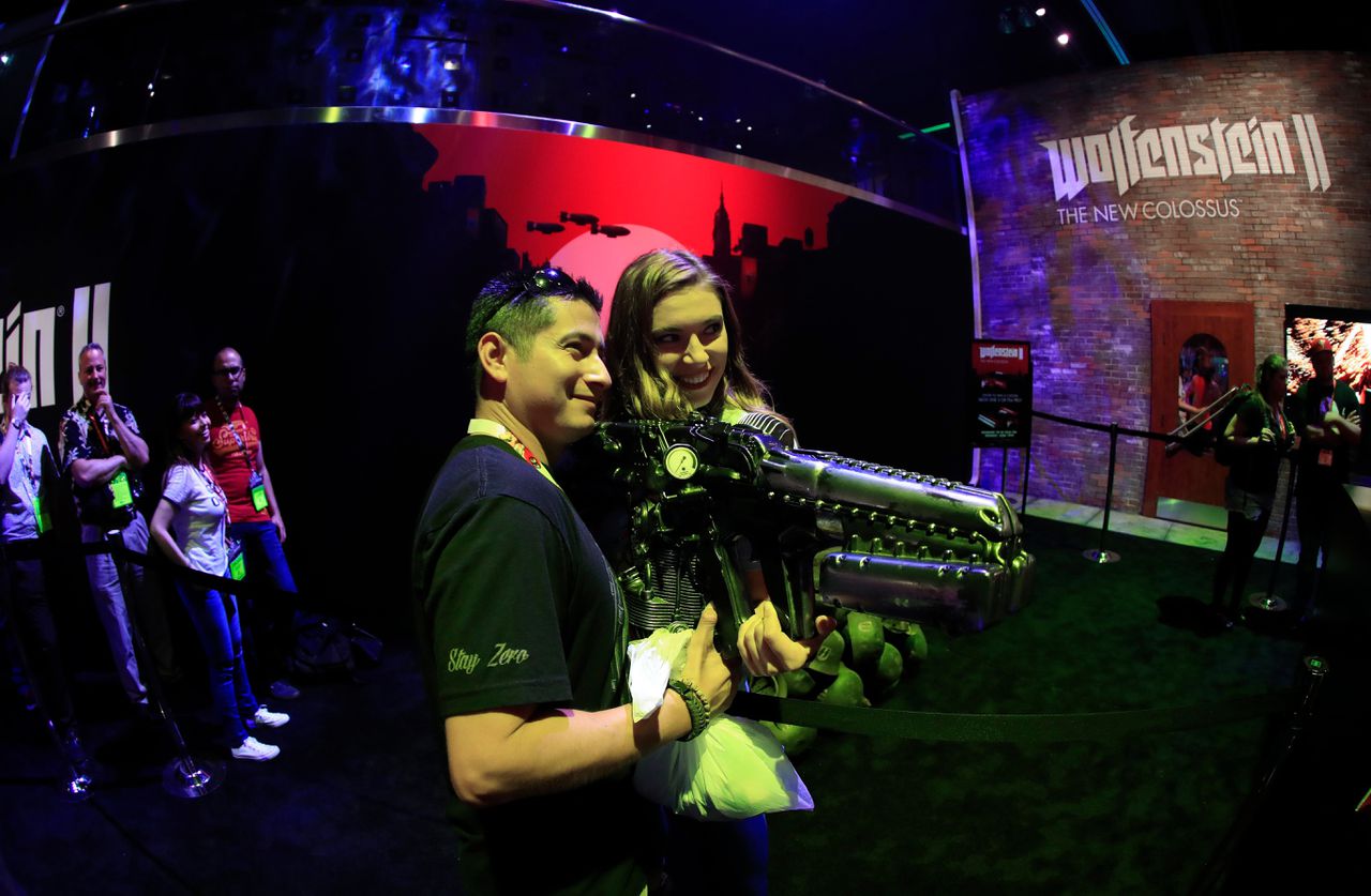Bezoekers van gamesbeurs E3 poseren met een wapen uit Bethesda’s schietspel Wolfenstein II:The New Colossus.