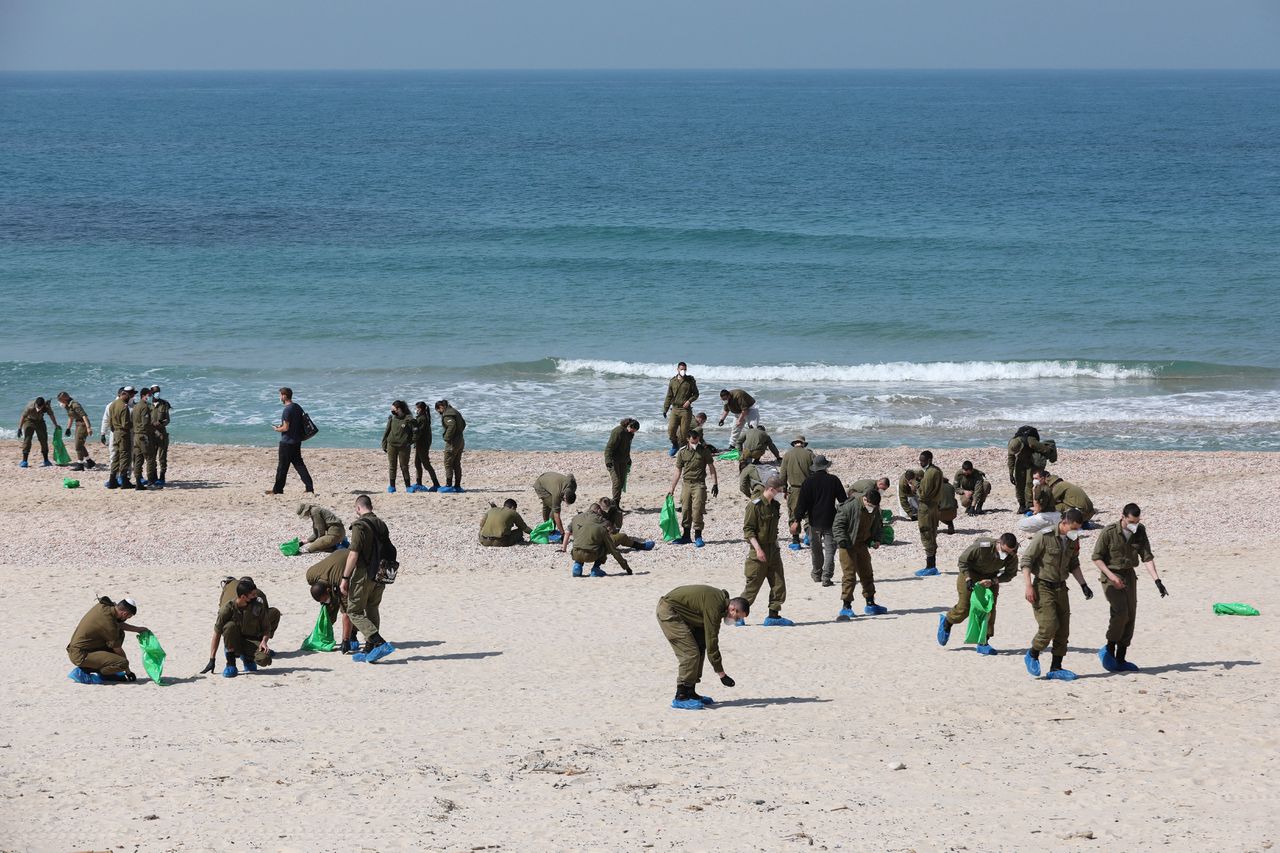 Israëlische soldaten en vrijwilligers rapen teerkorrels op het strand bij de stad Rishon Lezion