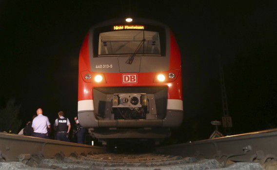 Politieagenten staan naast de trein in Wuerzburg waar maandagavond een Afghaanse asielzoeker vier mensen verwondde met een bijl en een mes. De dader werd doodgeschoten door de politie.