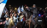 De bereden politie probeert demonstranten die een snelweg blokkeren tijdens protesten in Tel Aviv uiteen te drijven. 