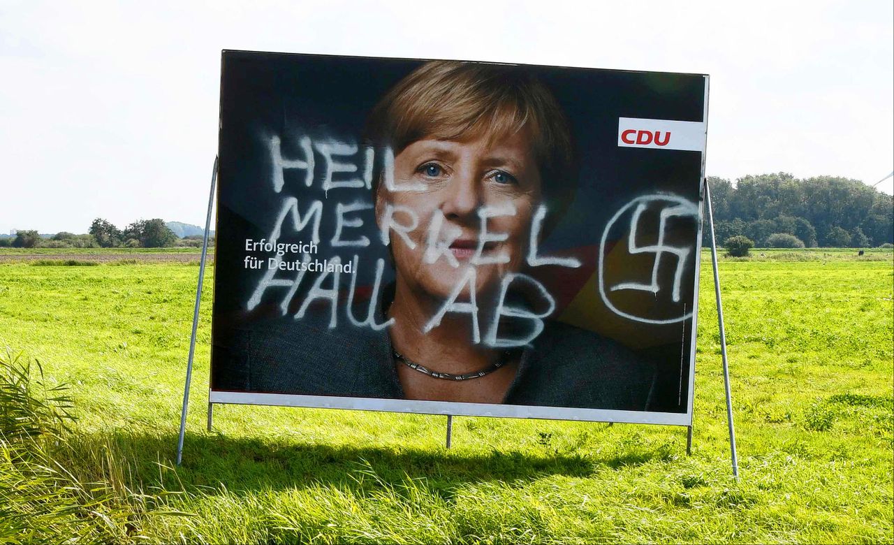 Verkiezingsposter van de CDU, beklad met de tekst 'Heil Merkel rot op'.