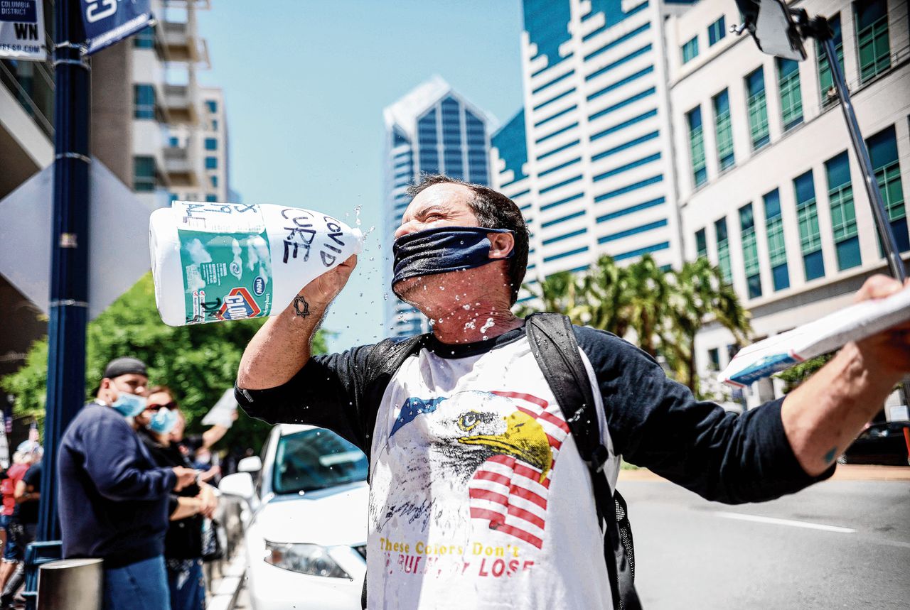 Een demonstrant tegen de lockdown in San Diego (VS) doet alsof hij bleekmiddel drinkt. Dat dat zou helpen tegen het coronavirus is een vorm van desinformatie.