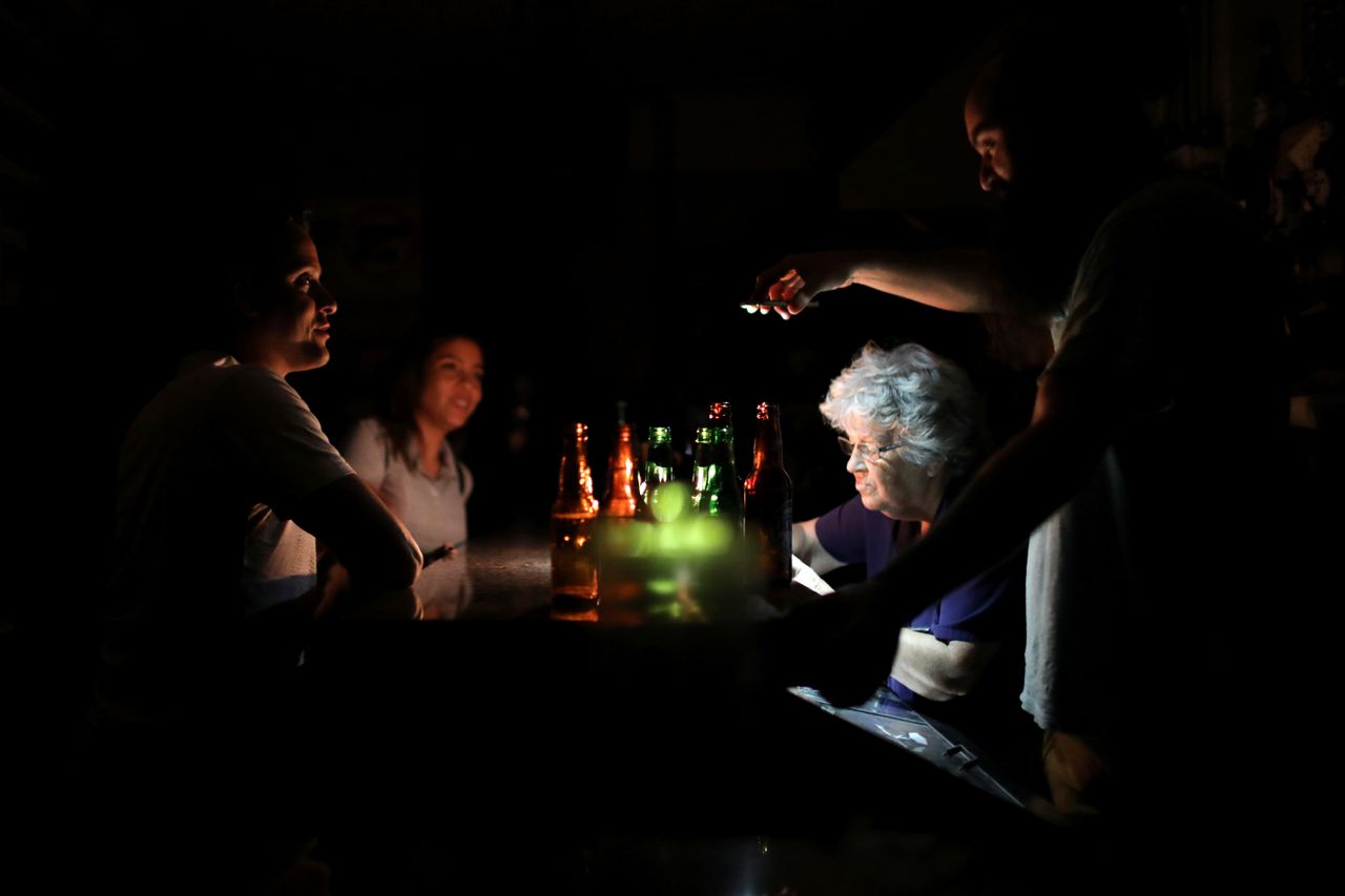 Een man gebruikt zijn mobiele telefoon om licht bij te schijnen in een bar in hoofdstad Caracas.