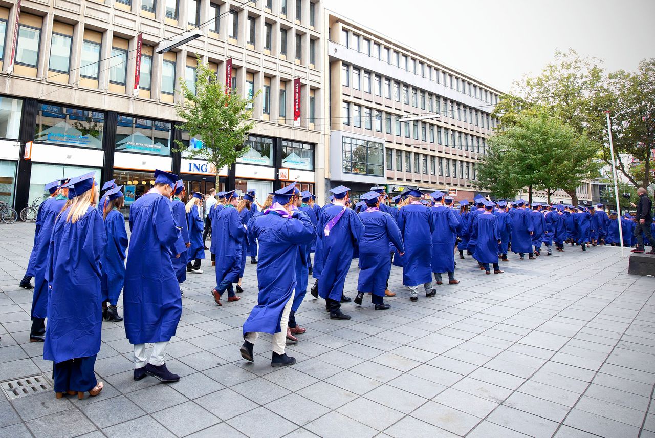 Afstudeerders van de Rotterdam School of Management (RSM) lopen in optocht door de binnenstad van Rotterdam.