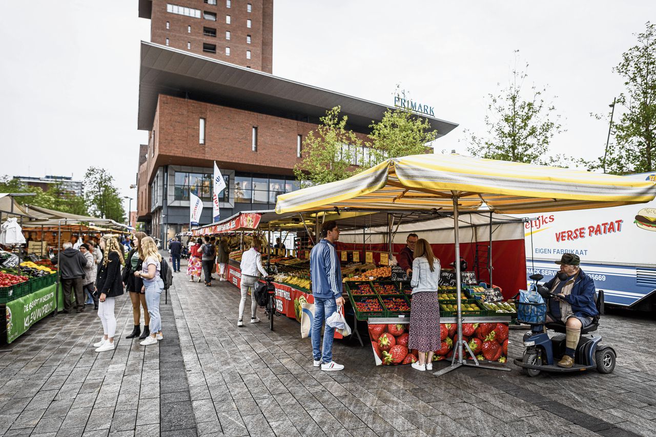 Mensen doen boodschappen op de markt in Enschede. Vooral huishoudens werden geraakt door de inflatie, zegt het CPB.