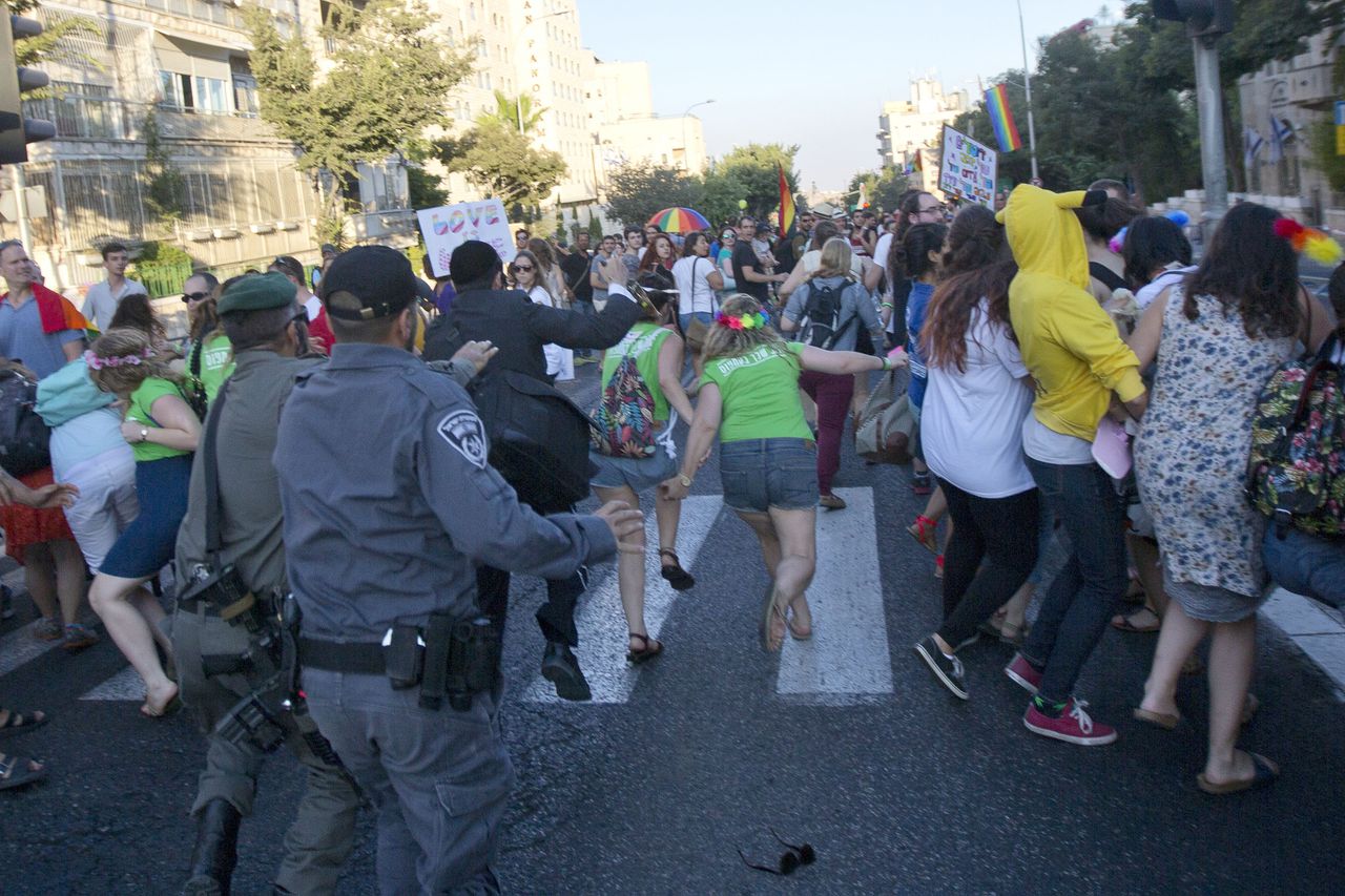 Leden van de Israëlische veiligheidsdiensten rennen achter Yishai Schlissel aan die op zijn beurt met een mes achter mensen aan rent tijdens de Gay Pride in Jeruzalem.