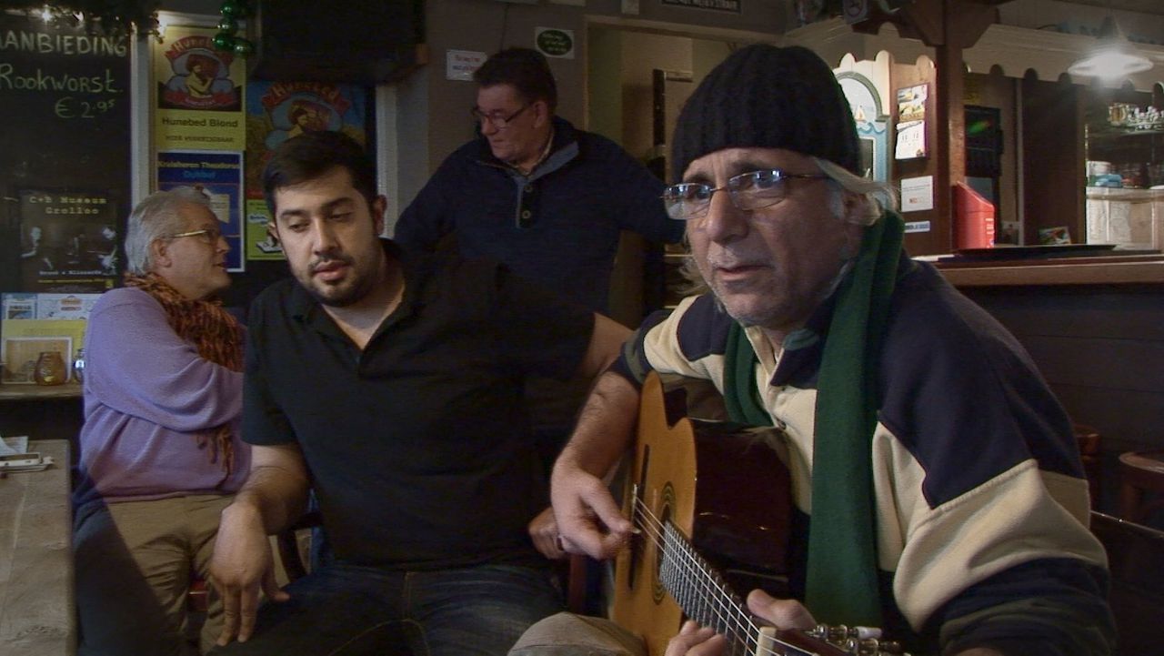 Een asielzoeker speelt gitaar in een lokaal café in de documentaire ‘Oranje - hoe een klein dorp groot in kan zijn’.