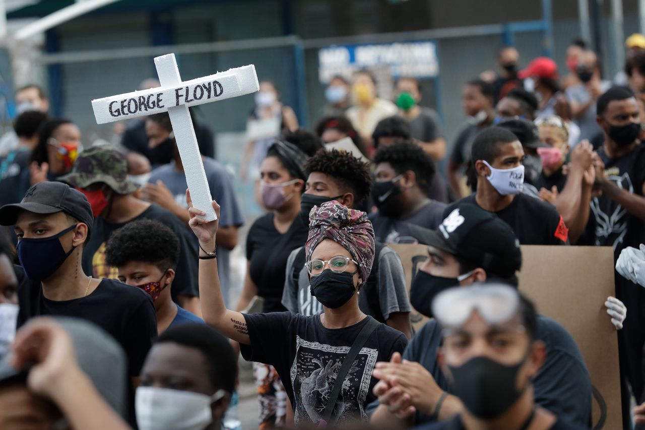 Demonstranten houden witte kruizen in de lucht tijdens een demonstratie tegen racisme en politiegeweld, deze zondag in de Braziliaanse stad Rio de Janeiro.