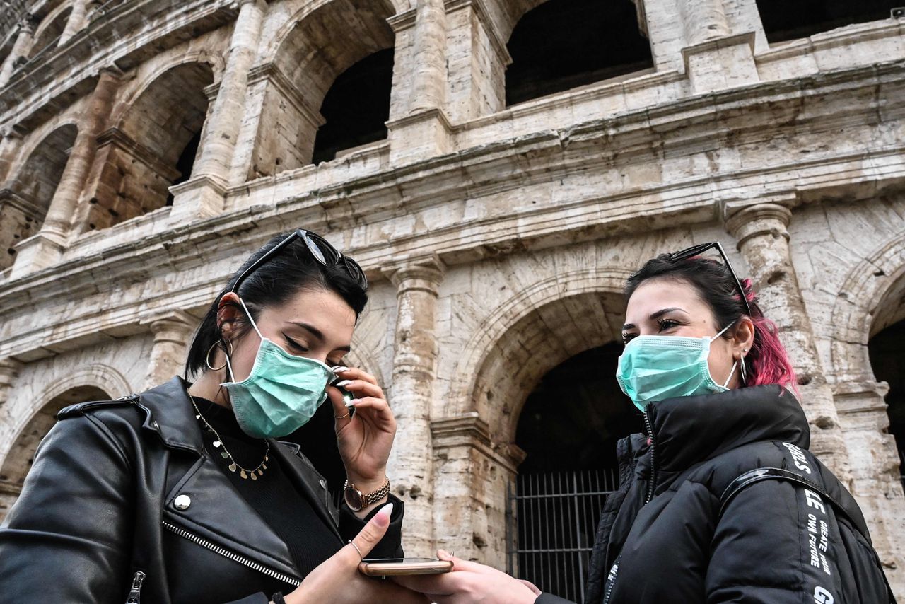 Twee Italiaanse vrouwen buiten het Colosseum in Rome dragen ook beschermende mondkapjes.