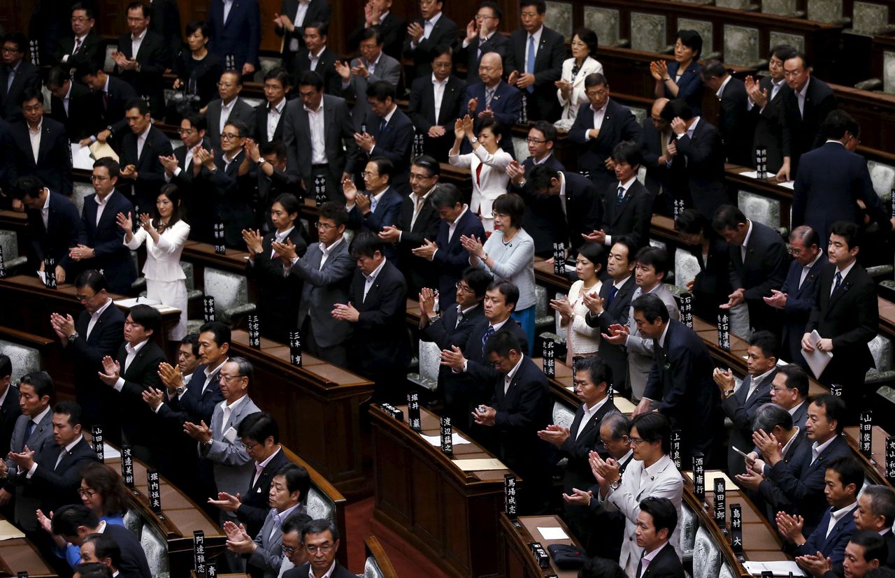 Leden van het Japanse Hogerhuis applaudisseren nadat ze de nieuwe oorlogswetten hebben aangenomen.