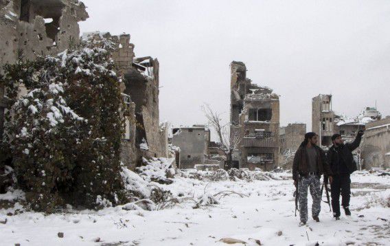 Rebellen van het Vrije Syrische Leger lopen door de verwoeste en ondergesneeuwde stad Aleppo.