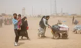 Terugkerende vluchtelingen duwen een handkar de grensovergang Islam Qala tussen Iran en Afghanistan over. Foto Muhammad Balabuluki / Middle East Images via AFP  