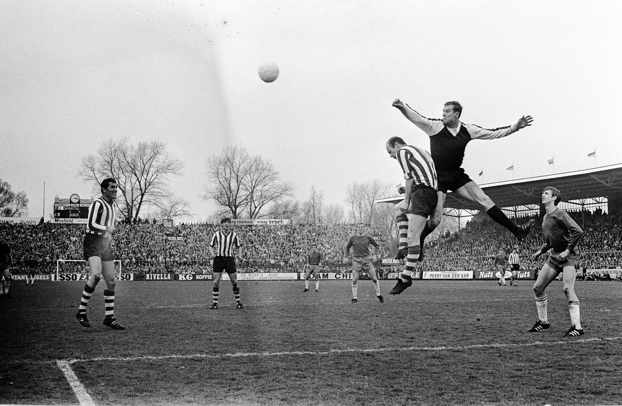 Sparta-doelman Jan van Beveren bokst de bal in 1968 met blote handen weg op het oude Kasteel. Rechts Ajacied Johan Cruijff, zijn latere kwelgeest bij Oranje.