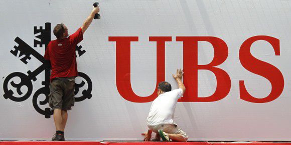 Construction workers erect an advertising banner for UBS, Switzerland's largest bank, the Singapore F1 Grand Prix race track in this September 24, 2010 file photo. Switzerland's UBS said on September 15, 2011 it had discovered that unauthorised trading by a trader in its investment bank has caused a loss of some $2 billion. UBS shares immediately tumbled 8 percent. REUTERS/Russell Boyce/Files (SINGAPORE - Tags: BUSINESS)