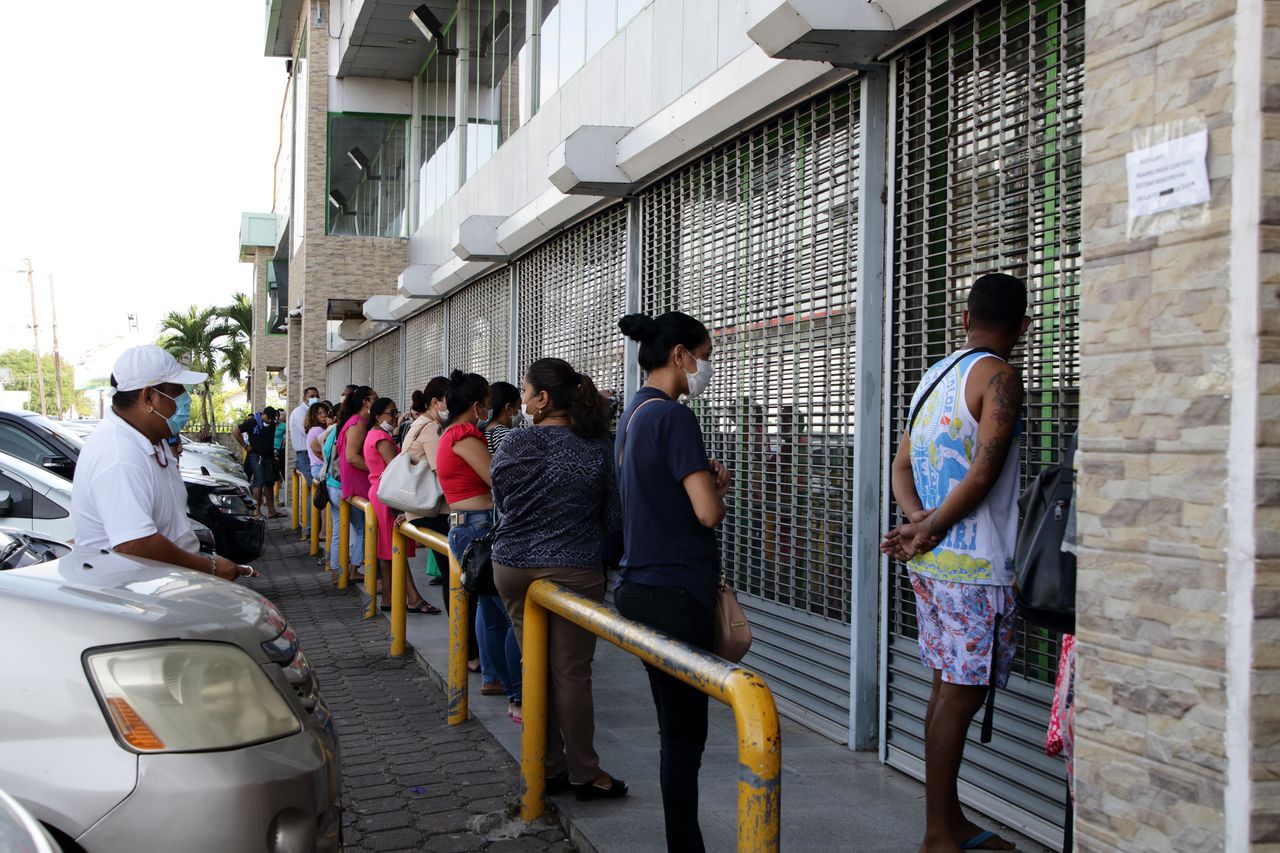 Archiefbeeld van Surinamers die wachten tot ze een supermarkt in Paramaribo kunnen betreden.