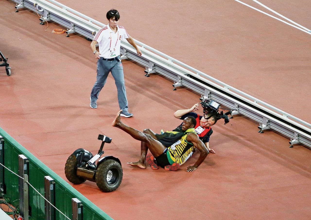 Usain Bolt werd tijdens het uitlopen na de finale van de 200 meter aangereden door een cameraman op een Segway.