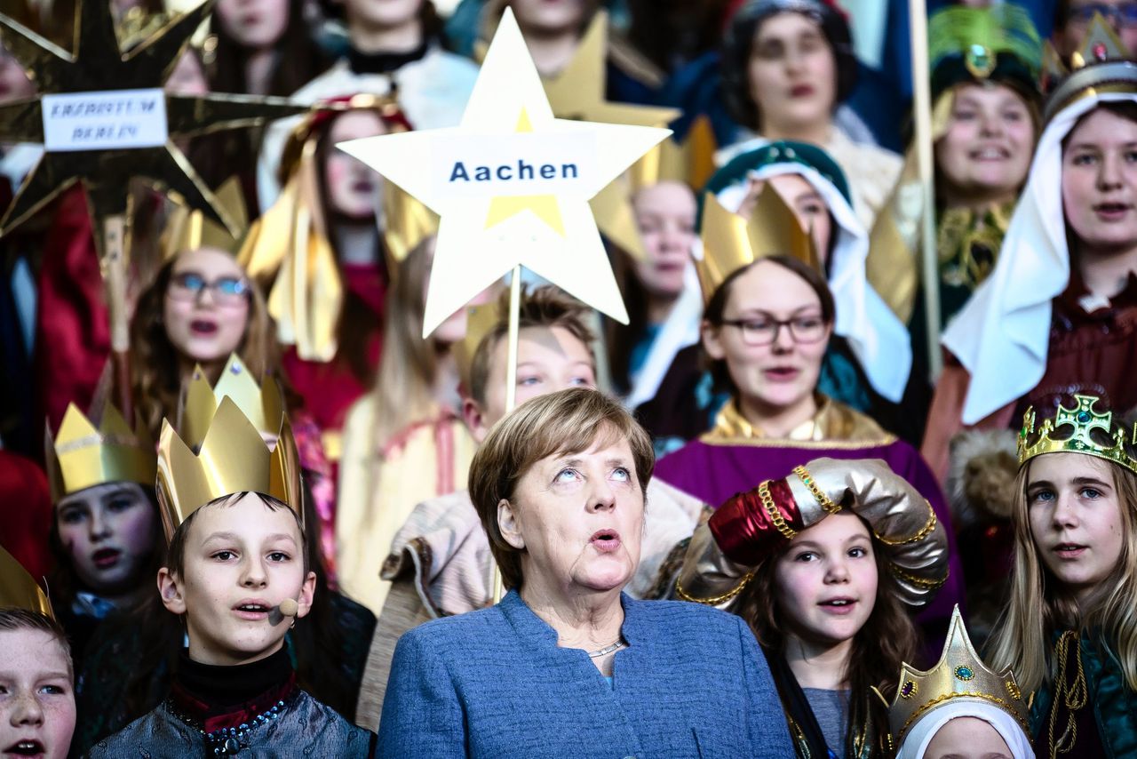 De Duitse bondskanselier Angela Merkel (m) zingt met kinderen tijdens een viering van Driekoningen.