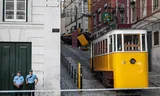 Politieagenten staan bij het politielint dat de woensdag ontspoorde tram moet afschermen van het publiek. Bij het tramongeluk kwamen zeker zestien mensen om. Foto Patricia de Melo Moreira/AFP 