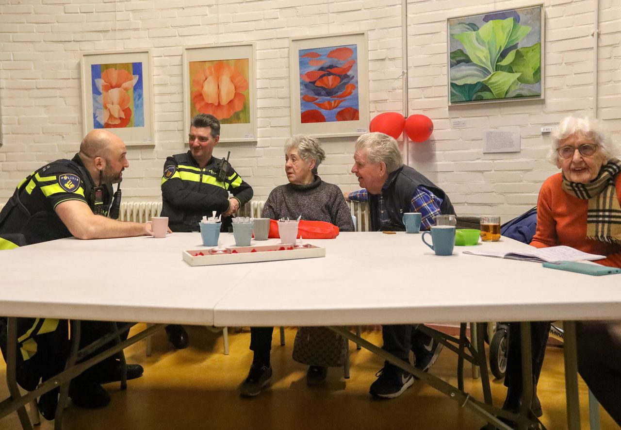 Wijkagent Cavit Koksal (links) praat met ouderen tijdens een informatiebijeenkomst over oplichting in Huis van de Wijk in Ommoord.