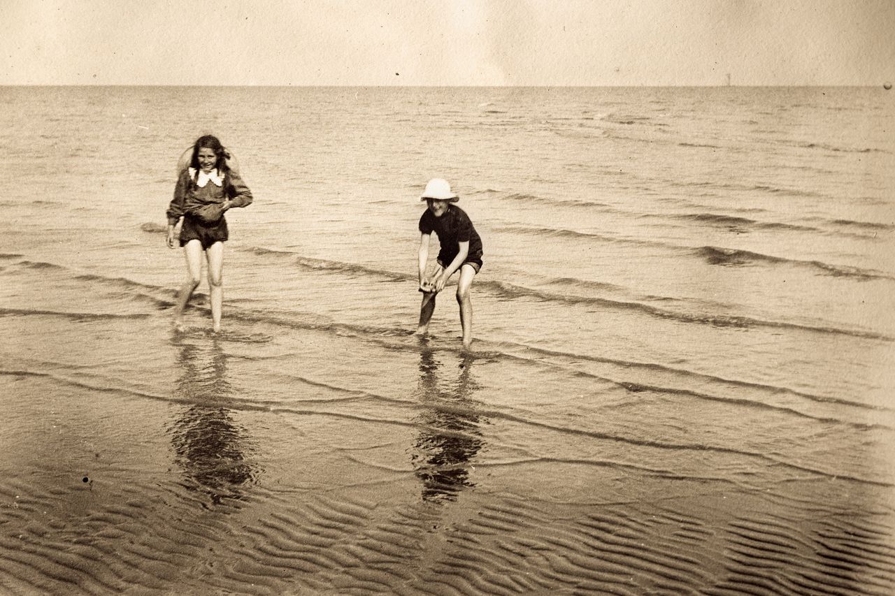 Kinderen spelen op het strand in het late victoriaanse of vroege edwardiaanse tijdperk.