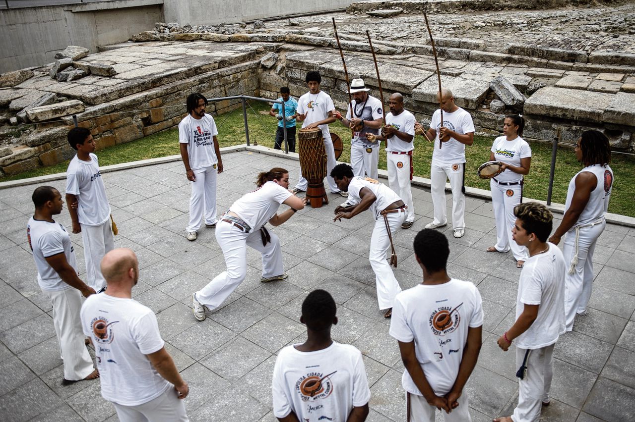 Brazilianen doen capoeira-oefeningen bij de voormalige slavenwerf. Deze door plantageslaven ontwikkelde vecht-verdedigingsdans is tegenwoordig het bekendste Braziliaans culturele exportproduct.