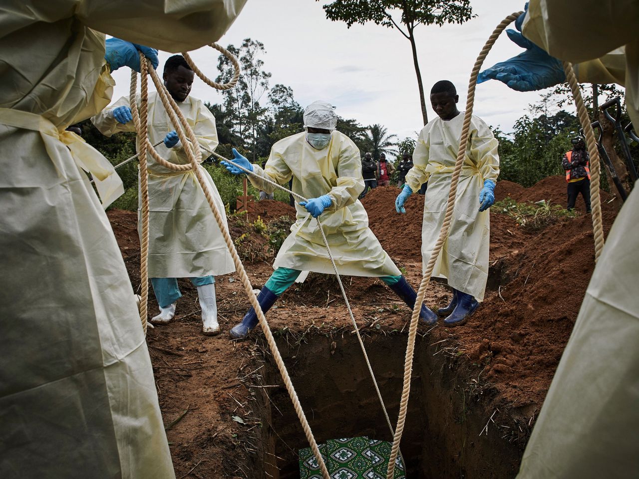 Hulpverleners laten de kist van een ebola slachtoffer zakken