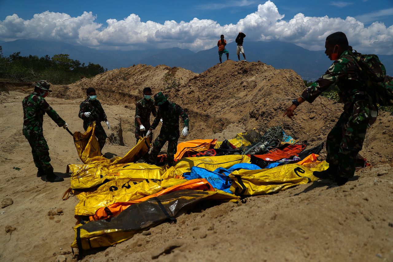 Soldaten verplaatsen de dode lichamen van slachtoffers naar een massagraf in Palu.
