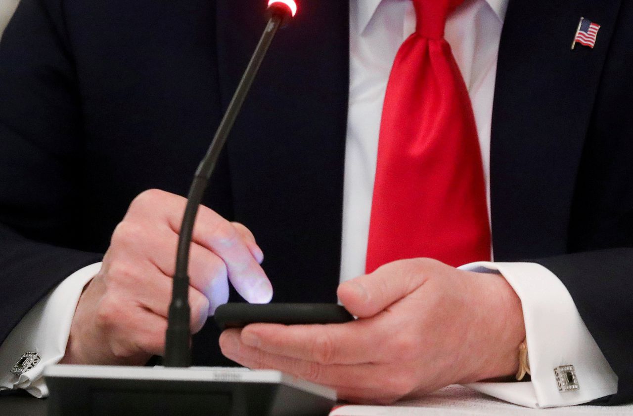 Oud-president Donald Trump gebruikt zijn telefoon tijdens een bijeenkomst in het Witte Huis in 2020.