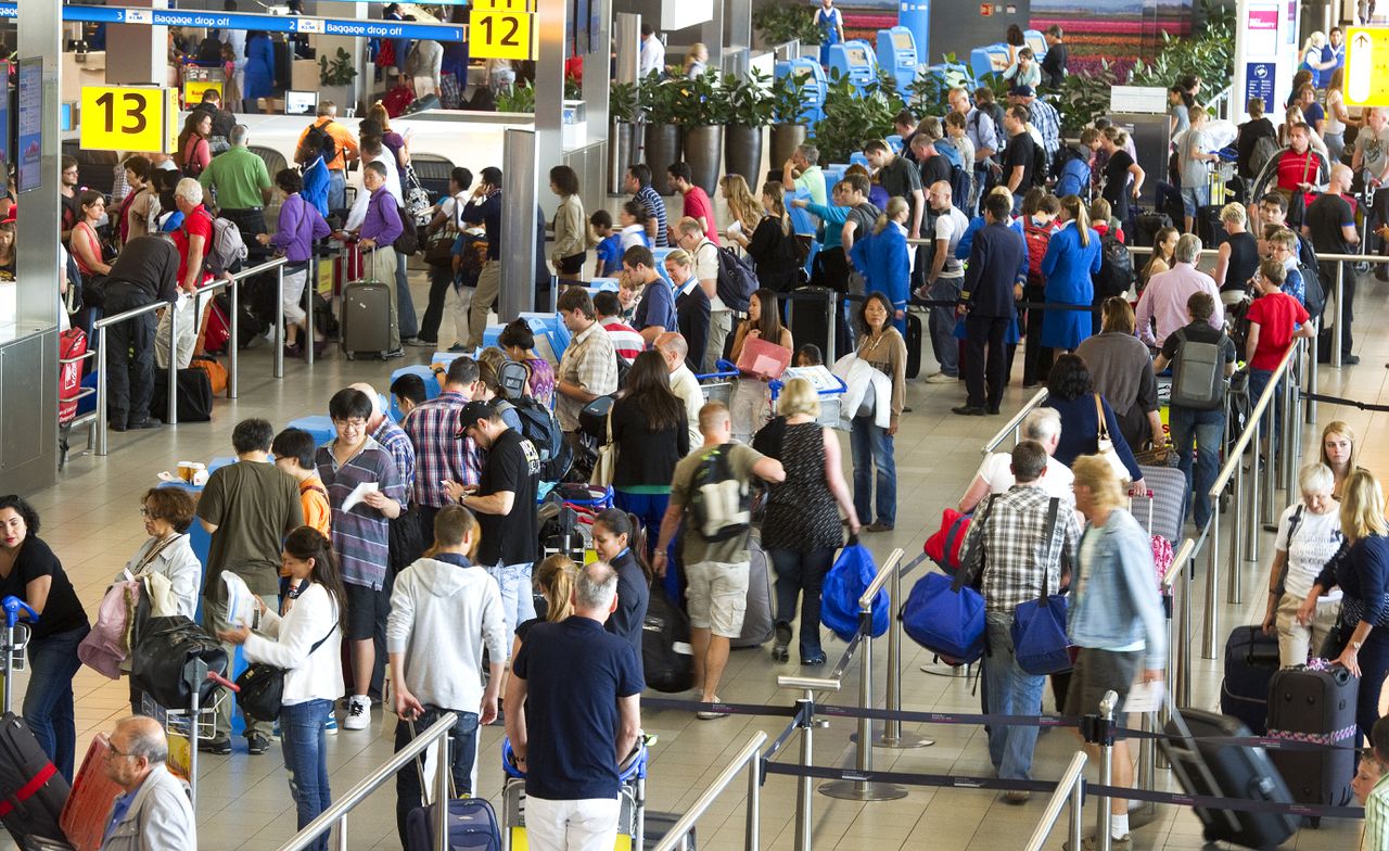 Drukte bij de check-in op Schiphol. Een deel van de Tweede Kamer vreest dat Lelystad straks een ongebruikt vliegveld krijgt.