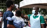Een gezondheidsmedewerker gebruikt een thermometer om mensen te controleren voor het Kibuli Muslim Hospital in Kampala, Oeganda, zaterdag 16 mei 2026. 