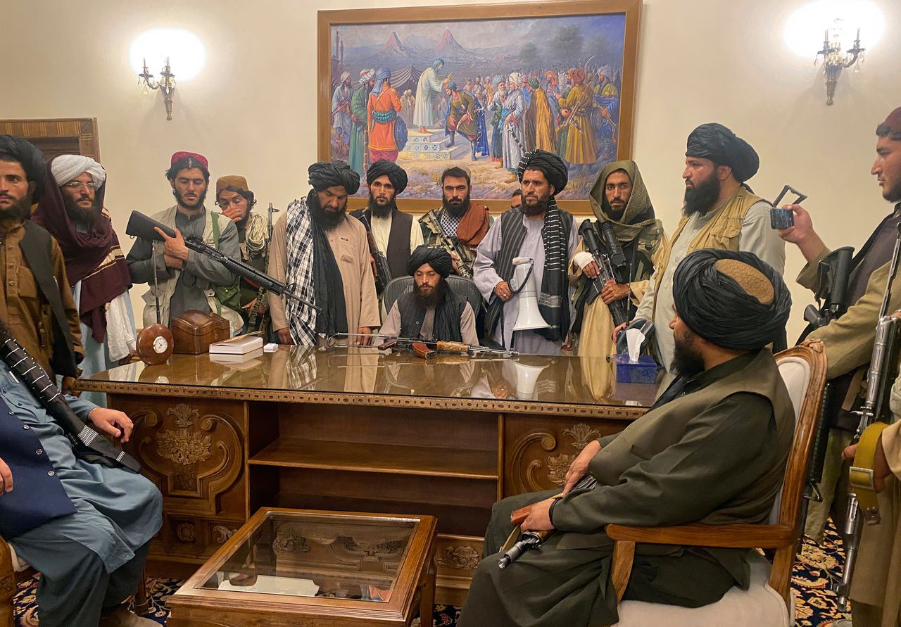 Talibanstrijders vanachter het presidentiële bureau in het paleis in Kabul.