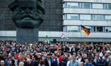 Rechtse betogers staan voor het beeld van Karl Marx in het Oost-Duitse Chemnitz.