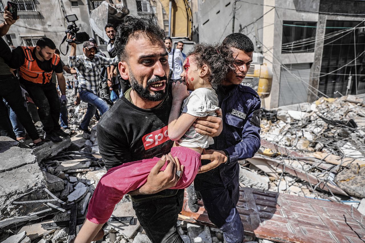 Een Palestijnse vader draagt zijn gewonde dochter uit de puin van een huis dat werd verwoest door een bombardement.