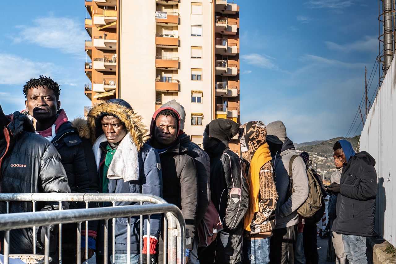 Migranten in de rij voor eten voor het gebouw van hulporganisatie Caritas in Ventimiglia.