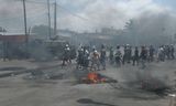 Demonstranten lopen op 6 december langs brandende  banden in Maputo, de hoofdstad van Mozambique, tijdens een demonstratie  in de nasleep van de betwiste verkiezingsuitslag.  Foto Amilton Neves / AFP 