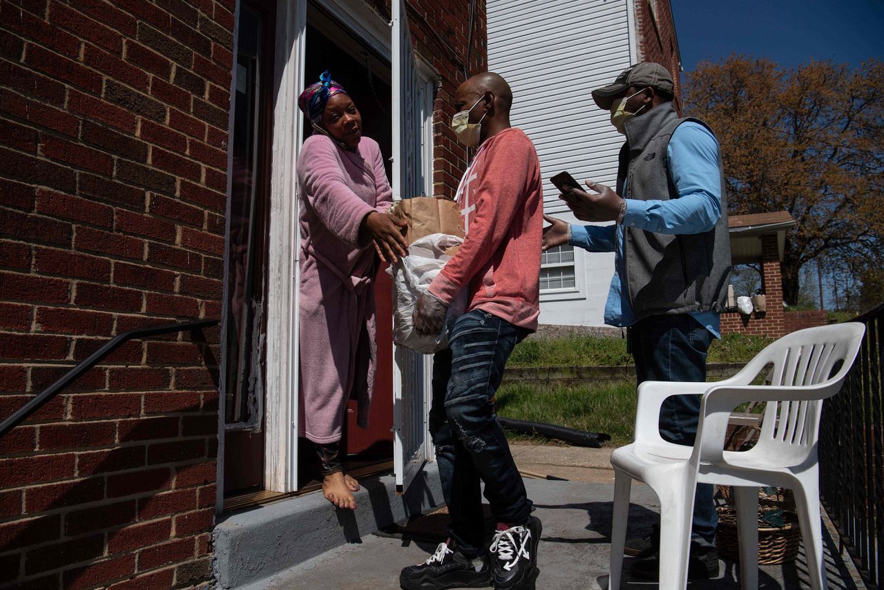 Twee mannen brengen boodschappen bij een vrouw in Washington. Het initiatief komt van een lokaal netwerk dat de armen en andere kwetsbare mensen ondersteunt.