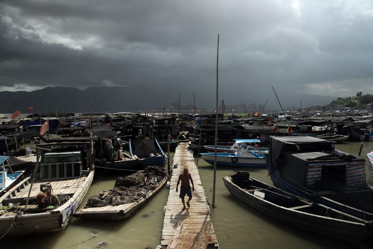 Een visser loopt op een pier in een veilige haven. Achter hem de aankomst van tyfoon Soudelor, in Ninge, in de zuidoostelijke Chinese provincie Fuijan.