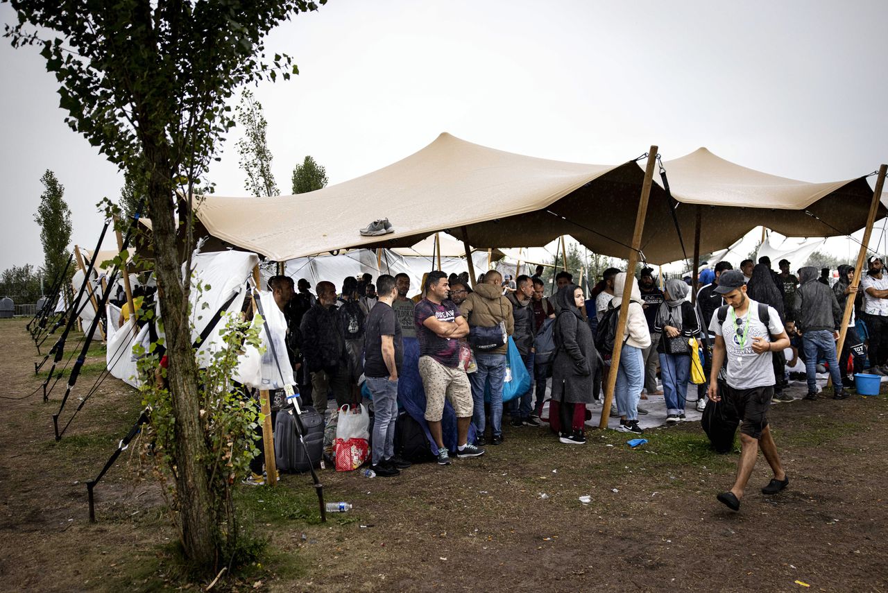 Asielzoekers onder een tentdoek bij het opvangcentrum in Ter Apel.