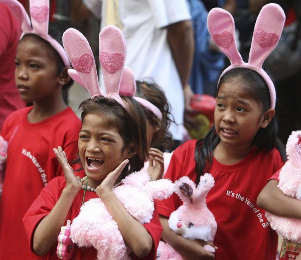 Kinderen dragen haarbandjes met konijnenoren en kijken naar festiviteiten in het teken van het Chinese Nieuwjaar in Manila's Chinatown op de Filipijnen.