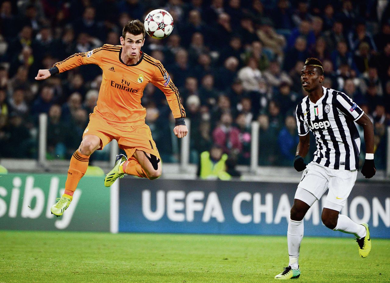 Gareth Bale van Real (links) kopt de bal weg voor Paul Pogba van Juventus.