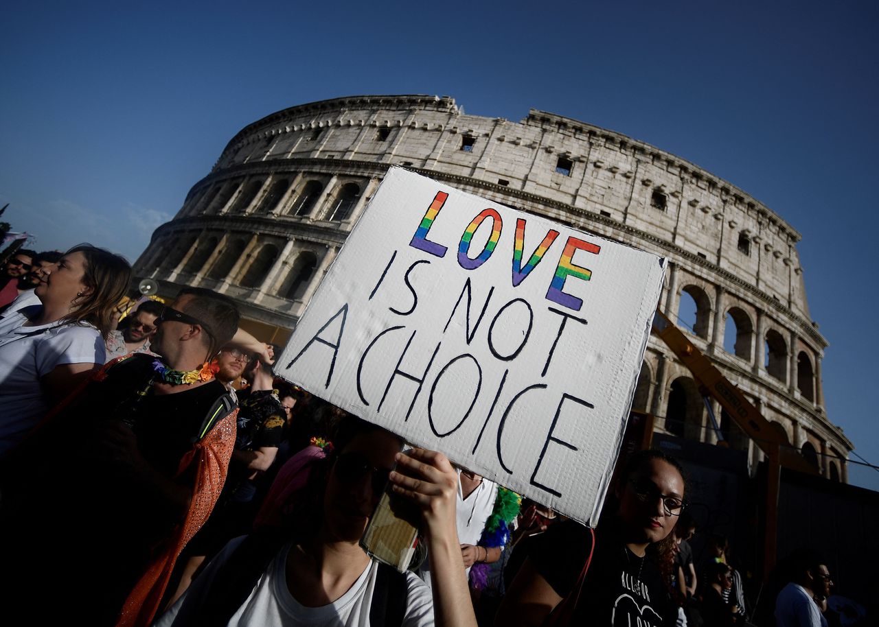 Een deelnemer van de Gay Pride in Rome houdt een bordje omhoog met de tekst 'Love is not a choice'.