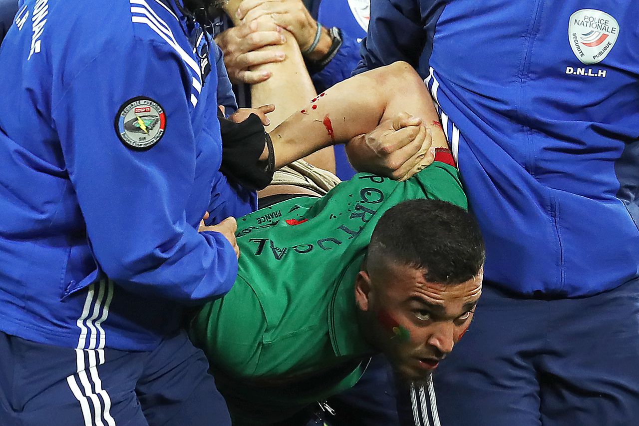 Een supporter wordt gearresteerd nadat hij het veld oprende tijdens de wedstrijd Polen-Portugal.