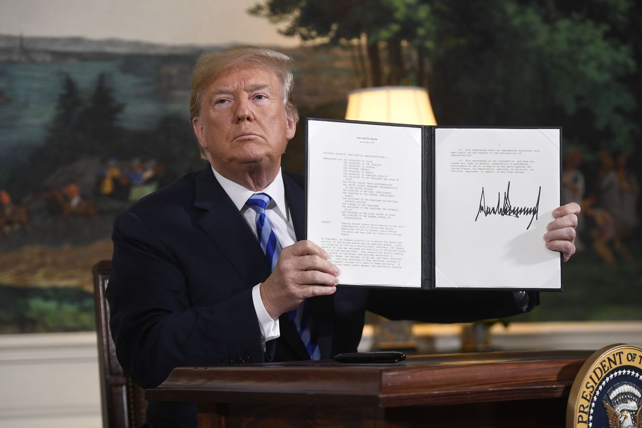 President Donald Trump houdt een document omhoog waarin staat dat er weer sancties tegen Iran worden ingesteld.