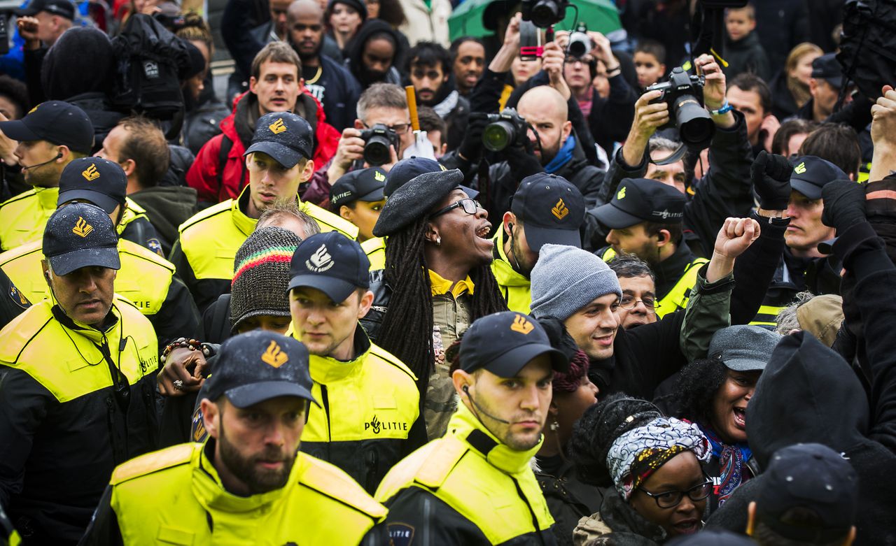 Agenten staan bij actievoerders die protesteren tegen Zwarte Piet tijdens de landelijke intocht van Sinterklaas.